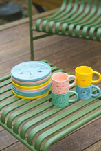Tasse mit Gesichtern in Türkis